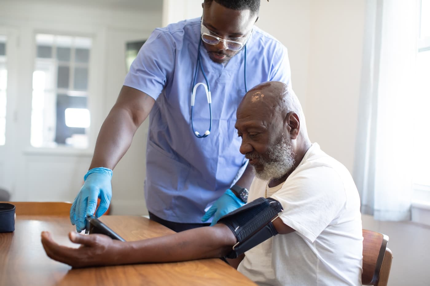 Nurse practitioner taking a blood pressure reading with a patient at home